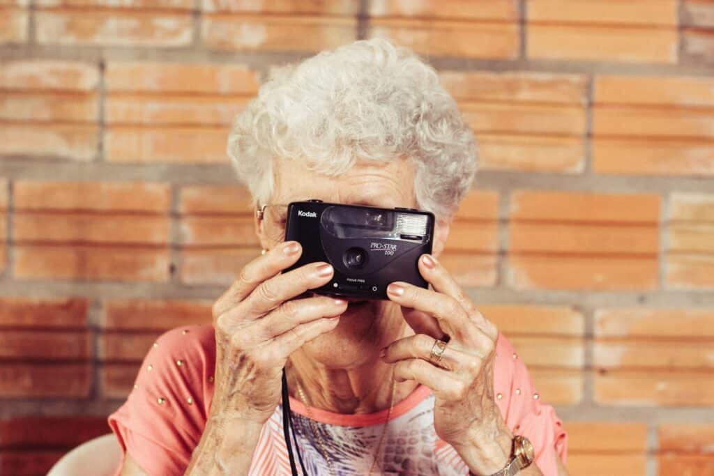 Starija žena sa fotoaparatom dobro raspoložena što govori da nije teškoda pomognete starijima da se presele u Beograd